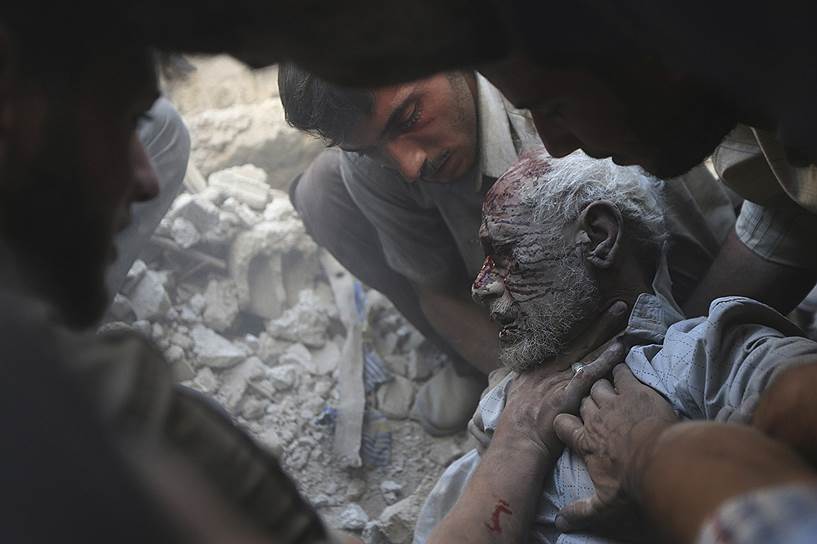 Местные жители вытаскивают пострадавшего из-под завалов разрушенного авиаударом дома в Думе, Сирия
