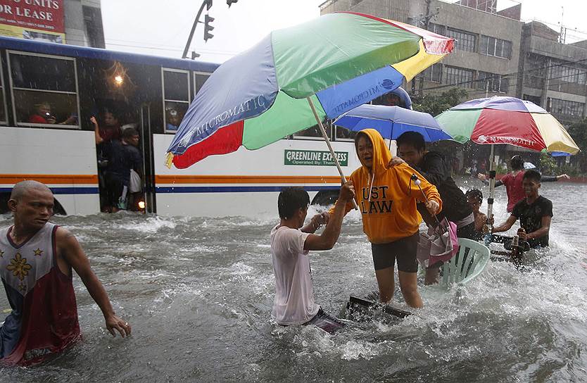 Люди на затопленной дороге в Маниле после прохождения  тропического шторма