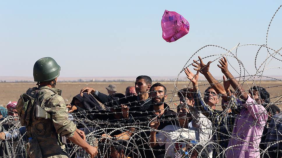 Тем временем Запад давит на Турци — его не устраивают открытые границы, через которые могут перейти боевики «ИГ»&lt;br>На фото: турецкий солдат кидает воду сирийским беженцам