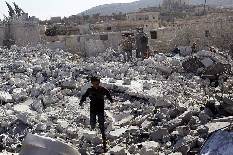 Местные жители осматривают здания, разрушенные при авиаударе ВВС США по позициям «Исламского государства» в сирийской провинции Идлиб