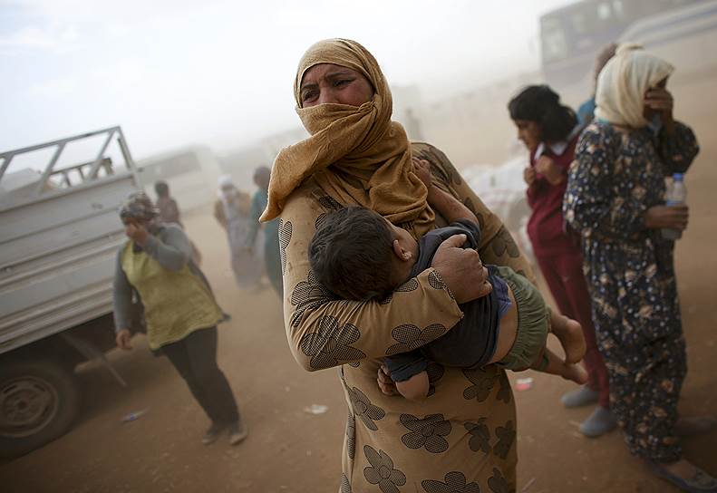 Сирийские беженцы во время песчаной бури на границе с Турцией