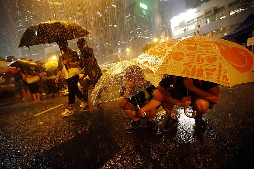 Участники массовых протестов в Гонконге пережидают дождь