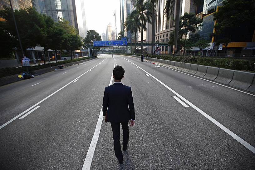 Мужчина идет по пустынной улице в районе финансового центра Гонконга, где в эти дни проходят массовые акции протеста