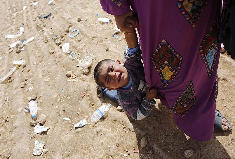 Беженка из Сирии с ребенком после пересечения границы с Турцией в районе города Суруч