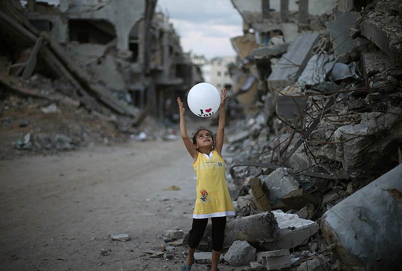 Палестинская девочка играет с воздушным шаром у своего разрушенного дома, Газа