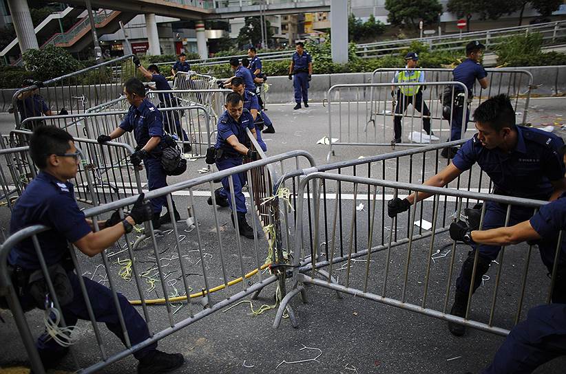 Сотрудники полиции разбирают баррикады, установленные демонстрантами в центре Гонконга