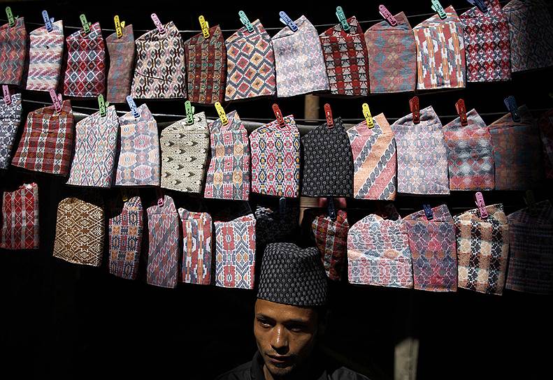 Продавец традиционных непальских головных уборов на улице в Катманду