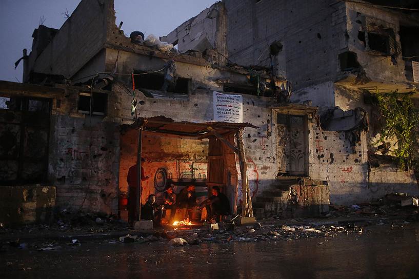 Палестинцы, укрывающиеся от дождя в разрушенной во время войны с Израилем Газе