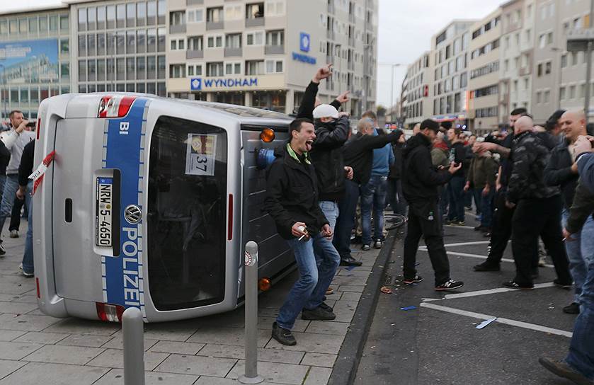 Автомобиль полиции, перевернутый во время акции протеста футбольных фанатов против радикальных исламистов в Кельне