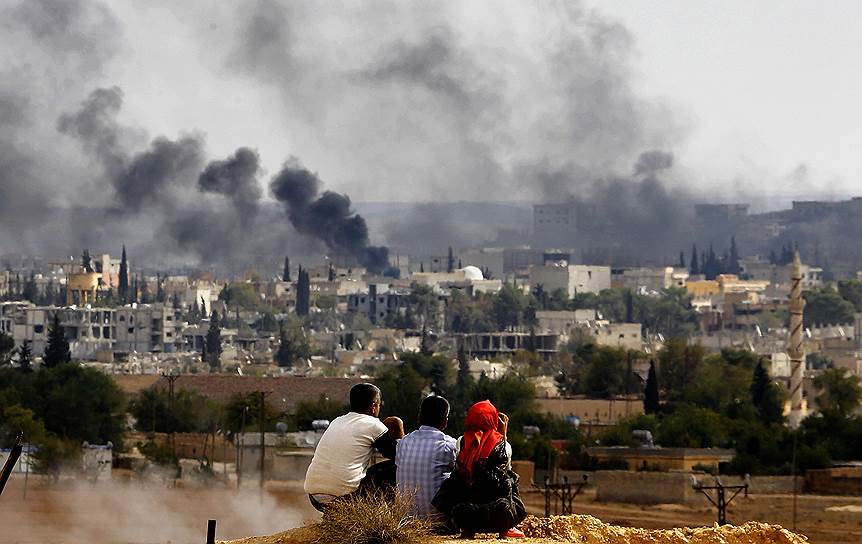 Беженцы из сирийского Кобани смотрят на свой город, за который идут бои между «Исламским государством» и курдской пешмергой