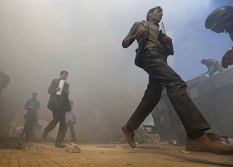 Сана, Йемен. Люди бегут от дыма, разносящегося от палаток сторонников демократии на площади Перемен, которые были снесены и подожжены правительственными войсками