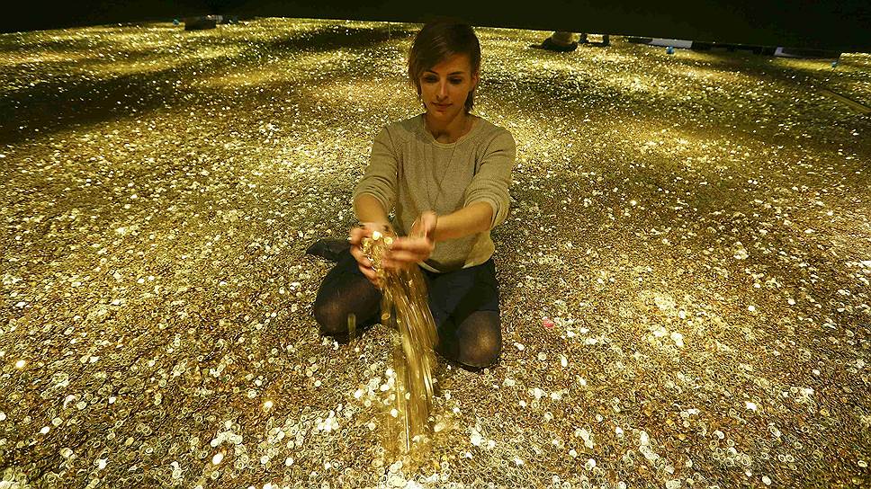 Ленцбург, Швейцария.  Девушка сидит на полу из 4 млн швейцарских пятицентовых монет во время пресс-показа выставки   Geld - Jenseits von Gut und Boese