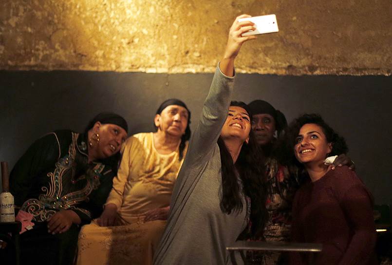 Каир, Египет.  Женщины фотографируются с музыкантами и целителями из группы Mazaher Zar после проведения традиционного ритуала экзорцизма 
