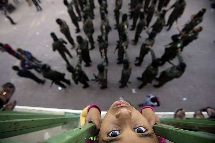 Рафах, Сектор Газа. Палестинская девочка наблюдает, как члены вооруженного крыла «Хамаса» участвуют в антиизраильском митинге 