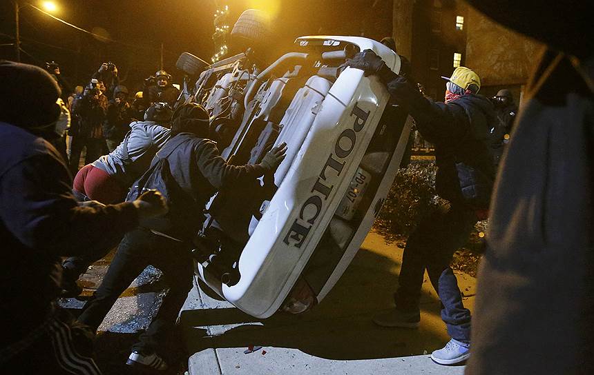 Фергюсон, США. Протестующие переворачивают полицейскую машину во время беспорядков