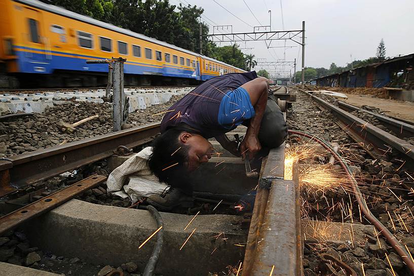 Джакарта, Индонезия. Рабочий отрезает часть железнодорожного полотна в ходе ремонта на участке линии в восточной части города