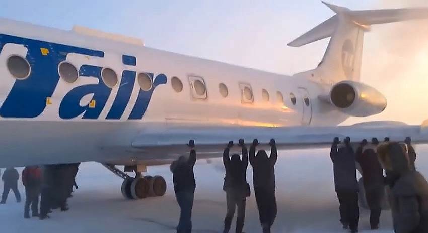 Пассажиры толкают самолет на взлетной полосое аэропорта города Игарки Красноярского края.