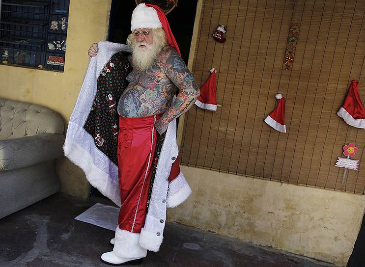 Сан-Каэтану-ду-Сул, Бразилия. Витор Мартинс, работающий Санта-Клаусом на праздниках и в торговых центрах, одевается перед выступлением для детей на городской площади. 94% поверхности тела господина Мартинса покрыты татуировками, в том числе и на рождественскую тематику