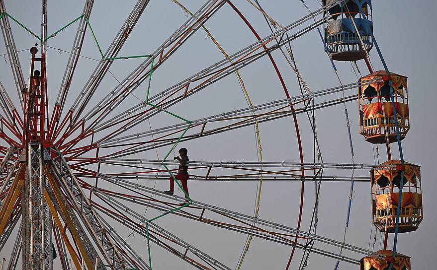 Мумбаи, Индия. Рабочий, устанавливающий иллюминацию на колесе обозрения