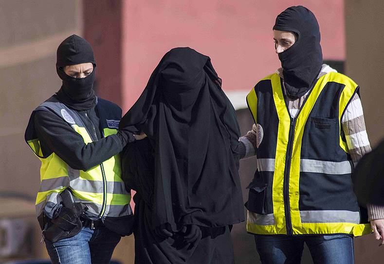 Мелилья, Испания. Сотрудники полиции в масках задерживают подозреваемую в найме и переправке женщин, поддерживающих «Исламское государство» в Сирию и Ирак 