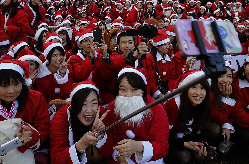 Токио, Япония. Одетые в костюмы Санта Клауса люди делают фотоснимки