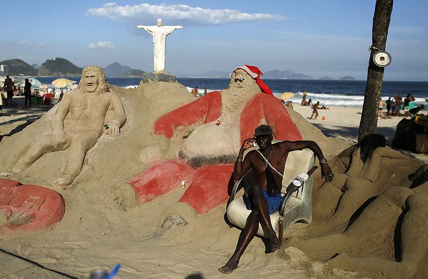 Копакабана, Рио-де-Жанейро, Бразилия. Мужчина позирует на фоне песчаных скульптур