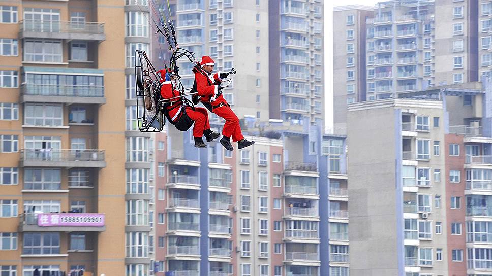 Провинция Гуйчжоу, Китай. Члены местного парашютного клуба, одетые в костюмы Санта-Клауса, разбрасывают подарки в ходе рождественской промо-акции 