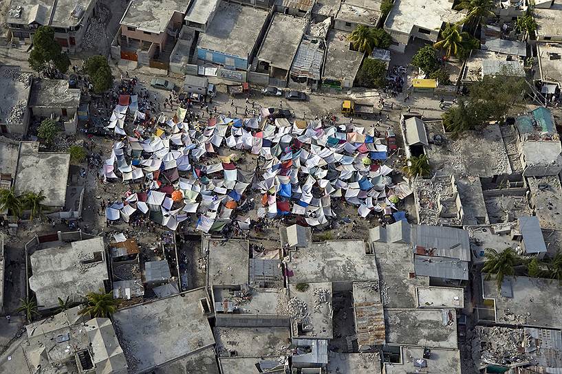 По оценкам властей, стихия разрушила более 50% зданий в столице, из-за повторяющихся подземных толчков жители Гаити опасались возвращаться в уцелевшие дома
&lt;br>
На фото: палатки среди обломков после землетрясения в Порт-о-Пренсе