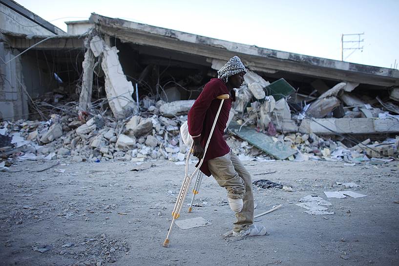 На фото: мужчина, потерявший в результате землетрясения ногу, идет по разрушенной улице Порт-о-Пренса