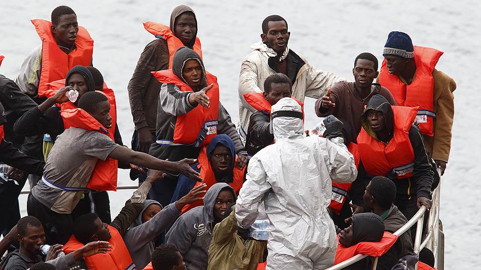 Валетта, Мальта. Мигранты из Африки, спасенные военным патрулем с тонущей лодки, тянутся за бутылками воды