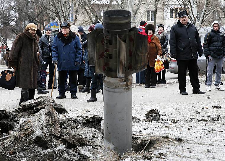 Краматорск, Донецкая область, Украина. Местные жители смотрят на неразорвавшийся снаряд после обстрела города, находящего под контролем украинских властей