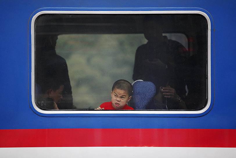 Хуэйчжоу, Китай. Мальчик корчит рожицу, сидя в поезде