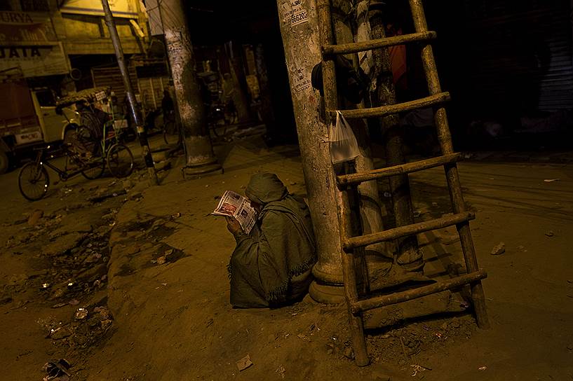 Нью-Дели, Индия. Бездомный читает газету в старом городе на рассвете