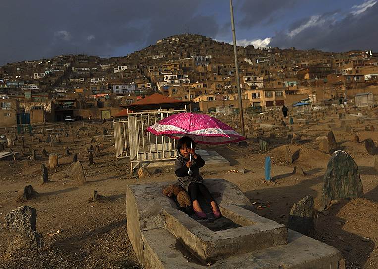 Кабул, Афганистан. Девочка с зонтиком на могиле на кладбище