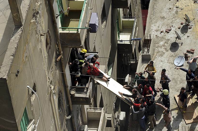 Каир, Египет. Эвакуация пожилой женщины с балкона горящего дома на крышу примыкающего строения