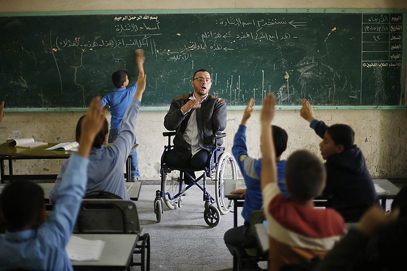 Газа, Палестина. 25-летний учитель, прикованный к инвалидному креслу после войны с Израилем, ведет урок в начальной школе