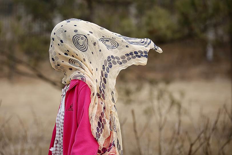 Пекин, Китай. Женщина с шарфом на голове, надетом для облегчения дыхания из-за сильного смога