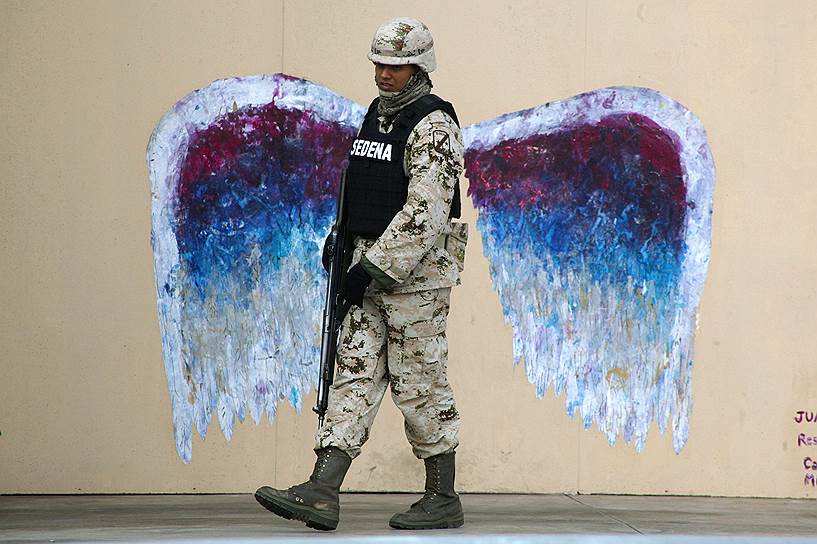 Сьюдад-Хуарес, Мексика. Солдат на фоне граффити, изображающего крылья ангела