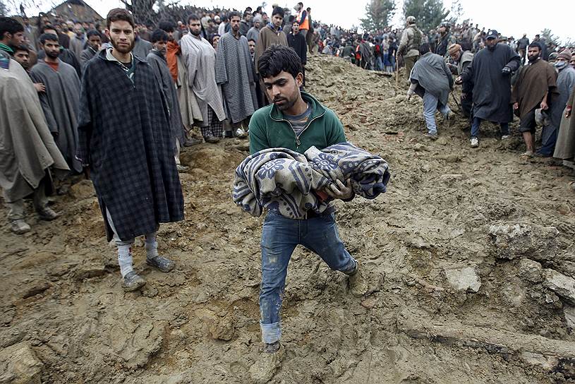 Штат Джамму и Кашмир, Индия. Местный житель несет тело ребенка, извлеченное из-под завалов дома, разрушенного оползнем