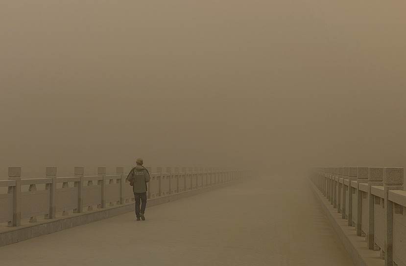 Дуньхуан, провинция Ганьсу, Китай. Мужчина на мосту во время пыльной бури