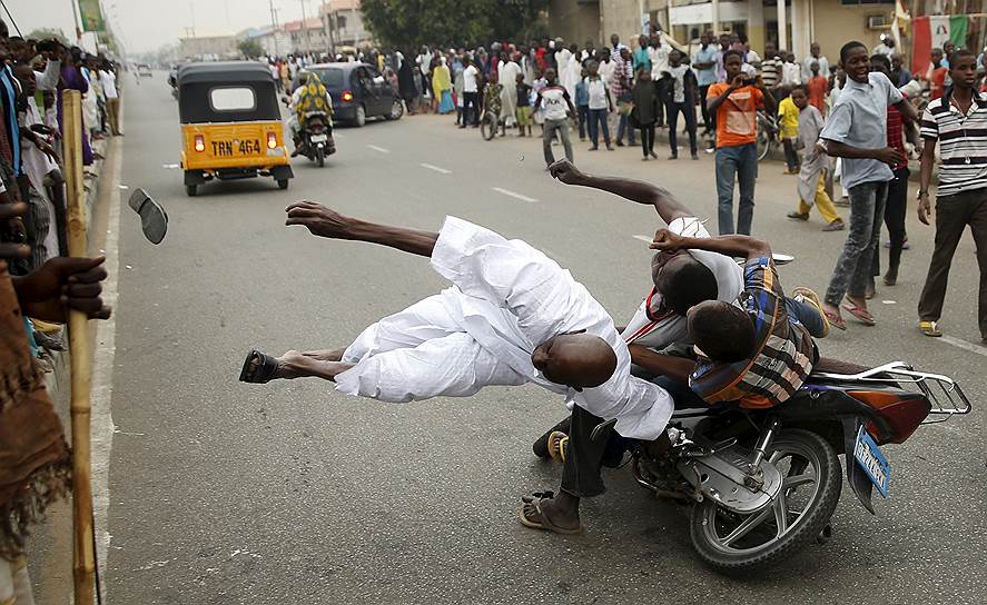 Кано, Нигерия. Сторонники кандидата в президенты страны Мухаммаду Бухари на мотоцикле толкают еще одного сторонника во время празднований