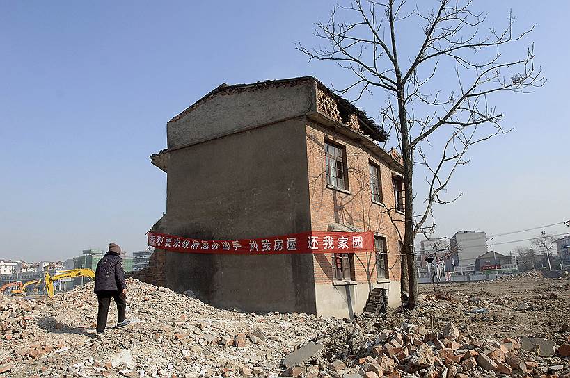 Владельцы «дома-гвоздя» (город Хэфей, провинция Аньхой) повесили плакат с требованием наказать застройщика, который намерен построить на этом месте современное здание