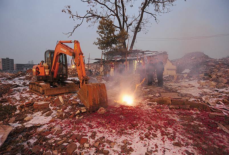 На фото: владелец снесенного дома в китайском городе Хэфей зажег фейерверк во время празднования Нового года
