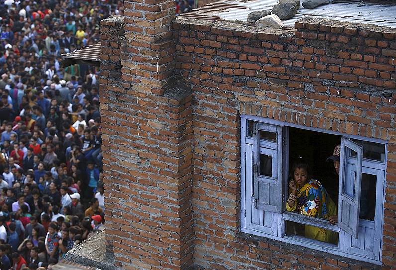 Бхактапур, Непал. Женщина наблюдает из окна за верующими во время праздника Бискет