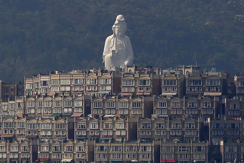 Гонконг, Китай. 76-метровая статуя бодхисаттвы Авалокитешвары, стоящая в монастыре Цз Шань, виднеется за жилыми зданиями