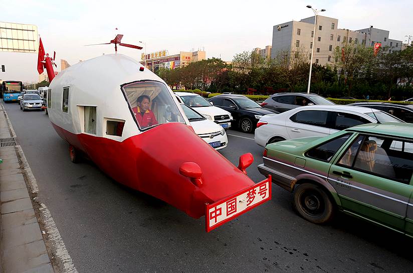 Чжэнчжоу, Китай. Юань Цзинин, инженер на пенсии, едет на своем самодельном автомобиле в форме вертолета
