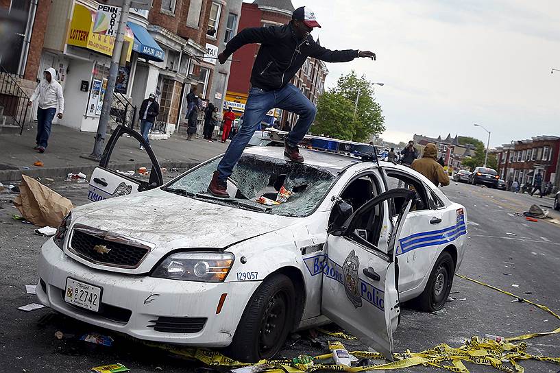 Балтимор, США. Демонстрант прыгает на капоте полицейской машины во время акции протеста