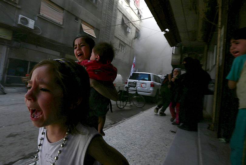 Дамаск, Сирия. Дети выбегают из Центра арабского Красного Полумесяца после обстрела, совершенного силами, лояльными президенту Сирии Башару Асаду