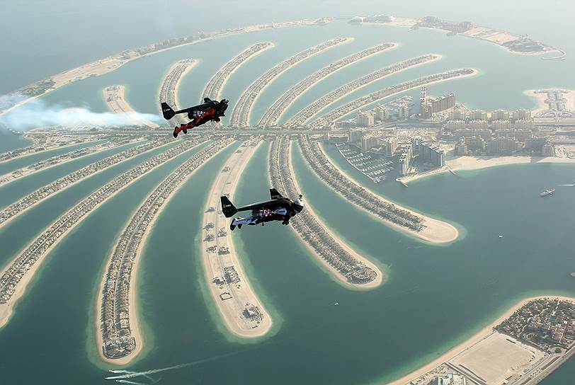 Дубаи, ОАЭ. Швейцарский изобретатель реактивного крыла-ранца Ив «Джетмен» Росси (на переднем плане) во время полета над искусствеными островами Пальм