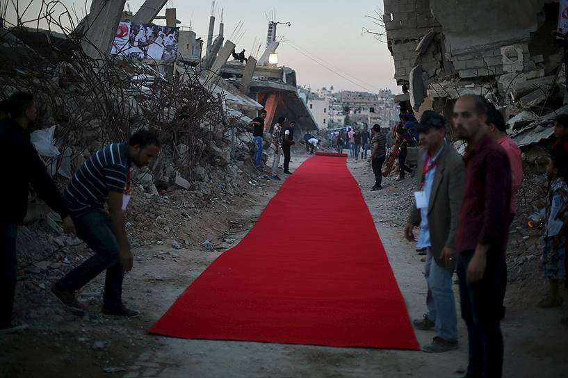 Газа, Палестина. Местные жители расстилают красную дорожку между домами, разрушенными в ходе войны с Израилем, перед премьерой фильма об этом конфликте